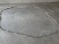 Une large fissure délimite une zone de la terrasse qui s'affaisse, révélant le gravier en dessous.