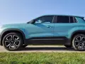 Turkusowy Jeep Avenger 4x4 z czarnymi felgami na tle nieba i trawy.