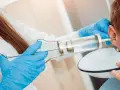 Lekarz płucze ucho pacjentowi, by usunąć woskowinę i pozbyć się nagłego zatkania ucha.