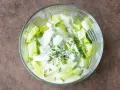 Erfrischender Gurken Dill Salat in einer Glasschüssel, cremiges Dressing mit frischen Kräutern.