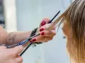 Fryzjerka precyzyjnie modeluje włosy, tworząc delikatne, **wispy bangs**.