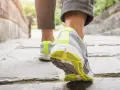Kobieta w sportowych butach idzie po kamiennej ścieżce. Czy chodzenie odchudza? Tak, regularny ruch to klucz do zdrowia i szczupłej sylwetki.