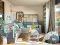 Salones muy pequeños con encanto: sofá gris, cojines coloridos, alfombra étnica, mesa de madera rústica y plantas.