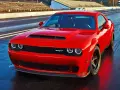 Czerwony Dodge Challenger SRT na torze wyścigowym. Potężny silnik 5.7 Hemi, choć jego spalanie może być wysokie, zapewnia niezapomniane wrażenia.