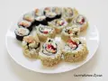 Talerz pełen sushi uramaki z łososiem, awokado i papryką, posypane sezamem. Pyszne i kolorowe rolki.