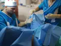 Chirurg i asystentka w rękawiczkach przygotowują się do zabiegu. Zdjęcia nieudana labioplastyka mogą pokazywać takie momenty.