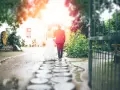 Para młoda idzie pod parasolem przez kamienną ścieżkę. W tle biały budynek i zielony ogród. To piękna brama weselna.