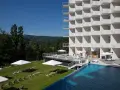 Nowoczesny hotel Crystal Mountain Resort z basenem i leżakami na trawie, otoczony zielonymi wzgórzami.