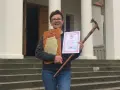 Uśmiechnięta kobieta z dyplomem i drewnianą laską, zdobywczyni Korony Gór Polskich.