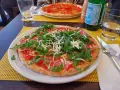 Leckere Pizza mit Rucola und Schinken auf einem Teller, ein Beispiel für glutenfreie Restaurants.