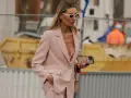 Donna con tailleur rosa, reggiseno a vista e occhiali da sole. Un look chic per ogni occasione.