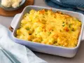 Herzhafter blumenkohl kartoffel auflauf mit geschmolzenem Käse und Petersilie garniert, bereit zum Servieren.