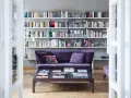 Un divano viola accogliente davanti a una libreria bassa piena di libri e CD.