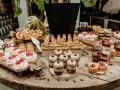 Słodki stół pełen pysznych ciasta na wesele: bezy z malinami, mini tarty, deserki w słoiczkach i inne słodkości.