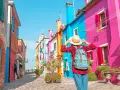 Una turista ammira le case colorate di Burano, un'isola raggiungibile con i traghetti da Chioggia.