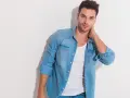 Uomo con un outfit camicia jeans, maglietta bianca e jeans.