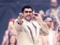 Bad Bunny w beżowym garniturze, z mikrofonem w dłoni, czuje energię tłumu.