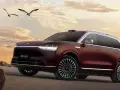 Ciemnoczerwony SUV Aito M9 na tle zachodzącego słońca, z ptakami w locie.