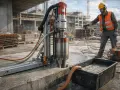 Robot budowlany wykonuje wiercenie dużych otworów w ścianie. Woda chłodzi wiertło i odprowadzana jest do pojemnika.