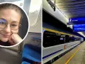Uśmiechnięta kobieta w okularach w pociągu, obok peron z tablicą informującą o odjeździe pociągu **Berlin Warszawa Express**.