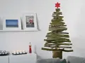 Ein rustikaler Tannenbaum aus Holzlatten, selbstgemacht, mit rotem Stern. Daneben Bilder und Kerzen.
