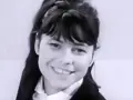 Uśmiechnięta Karin Stanek, jak malowana lala, w czarnym żakiecie i białej koszuli.
