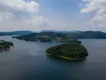 Widok z lotu ptaka na jezioro z wyspą porośniętą lasem i otoczone wzgórzami.