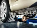 Mechanik sprawdza podwozie auta, szukając informacji o wymiana amortyzatorów cena.