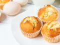 Puszyste babeczki z airfryer na białym talerzu, obok jajka. Idealne na szybkie śniadanie.