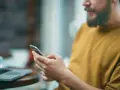 Uomo con barba usa smartphone, forse per capire cosa sono i gb del cellulare e quanto spazio ha per foto e app.