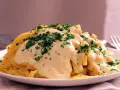 Pasta Alfredo cremosa con perejil picado en un plato blanco.