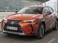 Pomarańczowy Lexus UX 250h w ruchu miejskim, z nowoczesnym grillem i reflektorami LED.