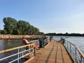 Ludzie odpoczywają i kąpią się nad zalewem Borki. Drewniane molo zaprasza do spacerów i podziwiania widoków.