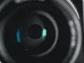 Ouverture d'objectif de caméra, diaphragme réglé sur f 2.8, révélant des reflets bleus et verts.