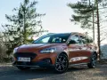 Pomarańczowy Ford Focus kombi na tle drzew i nieba.