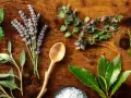 Variedad de hierbas frescas, incluyendo lavanda y romero, dispuestas sobre madera. Explora los usos de las hierbas provenzales en la cocina y aromaterapia.