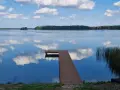 Spokojne jezioro Wągrowiec z drewnianym pomostem odbijającym chmury na błękitnym niebie.