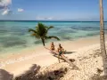 Para, gdzie w podróż poślubną! Para siedzi na przewróconej palmie na rajskiej plaży, z turkusową wodą w tle.