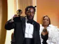 Artysta w garniturze odbiera nagrodę Grammy: najlepsza piosenka - rap.