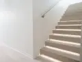 Scala moderna con gradini in legno illuminati e un discreto profilo battiscopa filo muro che ne esalta la pulizia delle linee.