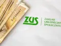 Pieniądze i logo ZUS. Symbolizuje to świadczenie rehabilitacyjne, które można uzyskać dzięki ubezpieczeniu społecznemu.