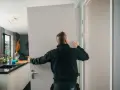 Pracownik montuje drzwi, tworząc wykucie otworu na drzwi w nowoczesnym wnętrzu.
