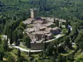 Il castello di Gargonza, un borgo medievale in pietra con torre, immerso nel verde della Toscana.