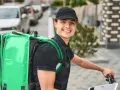 Uśmiechnięty kurier Bolt Food z zieloną torbą na plecach, gotowy do pracy i dobrych zarobków.