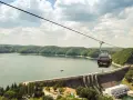 Kolejka gondolowa nad zaporą w Solinie, z widokiem na jezioro i zalesione wzgórza.
