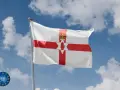 Flaga Irlandii Północnej powiewa na tle błękitnego nieba z chmurami. Symbolizuje historię i tożsamość regionu.