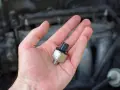 A hand holds a new oil pressure sensor, a potential fix for a p0332 code Chevy Silverado.