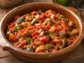 Un delicioso pisto de calabacín, pimientos y tomate en una cazuela de barro. ¡Perfecto para aprender como hacer pisto de calabacín!