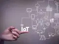 A hand points to the word "IoT," illustrating the vast network of connected devices and systems that offer significant **iot benefits for business**, from smart homes to factories.