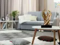 Esculturas de manos doradas, arte moderno que adorna un salón acogedor con sofá gris y alfombras mullidas.